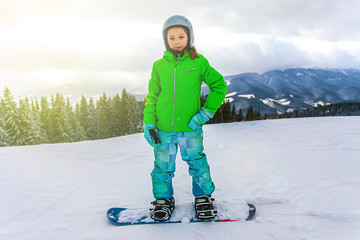 Cute child girl is snowboarding on the snow mountain