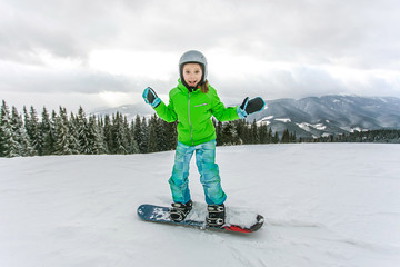 Cute child girl is snowboarding on the snow mountain