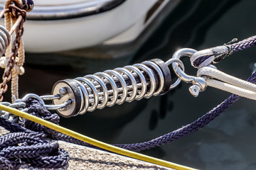 Metal cleat for mooring boats, bolted to the ground, with rope and shock absorber spring