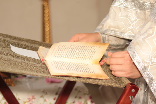 priest's hands on bible in church while reading prayer