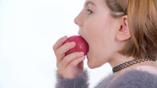 A young girl is decididing to try out a small red apple.