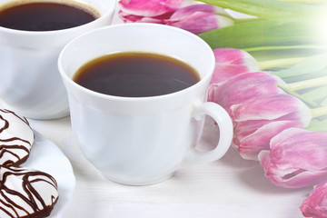 Two cups of coffee,cake and pink tulips on white background
