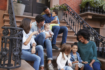 Two families with kids sitting on front stoops