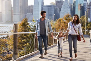 Young family with daughter taking a walk on footbridge