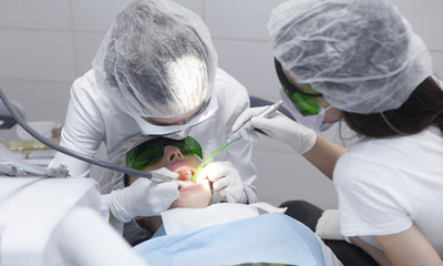 Obraz na płótnie Canvas Young female patient visiting dentist office.Beautiful woman with healthy straight white teeth sitting at dental chair with open mouth during a dental procedure.Dental clinic. Dental caries
