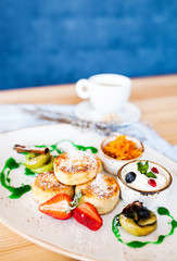 beautiful breakfast: curd puncakes with cranberries, figs, strawberries and sour cream with a cup of coffee