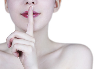 Naklejka premium Close up of young woman's face smiling with red lips showing silence gesture on white background - secret concept