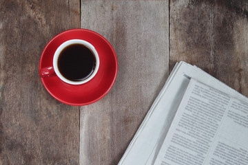 Red coffee cup and news paper on wood table