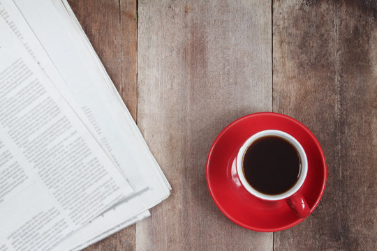 Red coffee cup and news paper on wood table