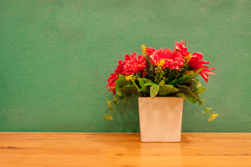 Fake flowers in pot with green background.
