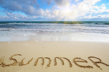 Word Summer written on sand at ocean beach summer time