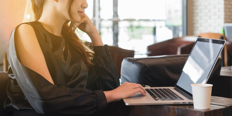 Beautiful asian woman in black dress working with laptop in coffeeshop