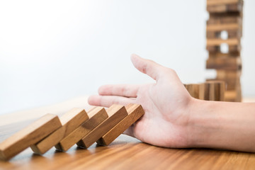 businessman hand stop dominoes continuous toppled or risk with copyspace.