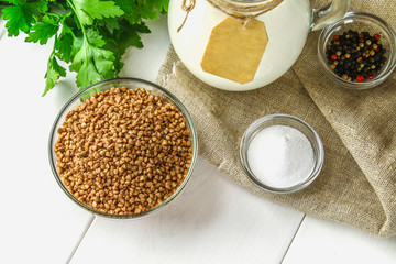 Raw buckwheat in glass bowls on sackcloth on a wooden background. Healthy diet food.