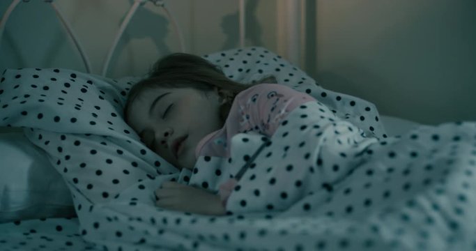Young Girl Sleeping and Rolling Over at Night Move Left. view moves left on a girl sleeping in her bed at night under the covers and rolls over with a pok-a-dot sheets and pillow