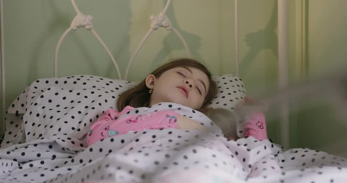 Young Girl Sleeping in Morning Move Left. view moves left on a girl sleeping in her bed in the morning under the covers with a pok-a-dot sheets and pillow
