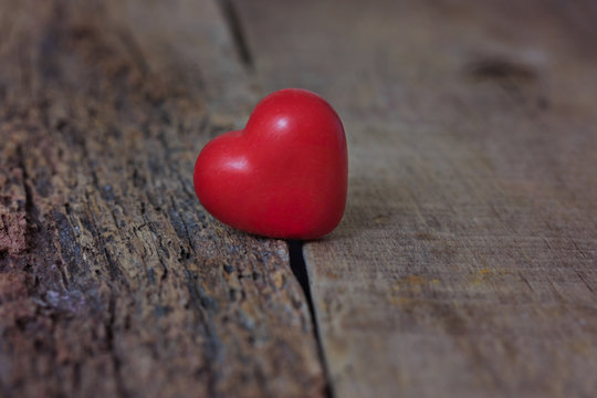 The red heart lies on the cracks of the tree. The separation, loneliness, love. Valentine's Day.