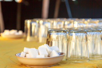 Two plates containing sugar cubes and several upside down glasses on a table