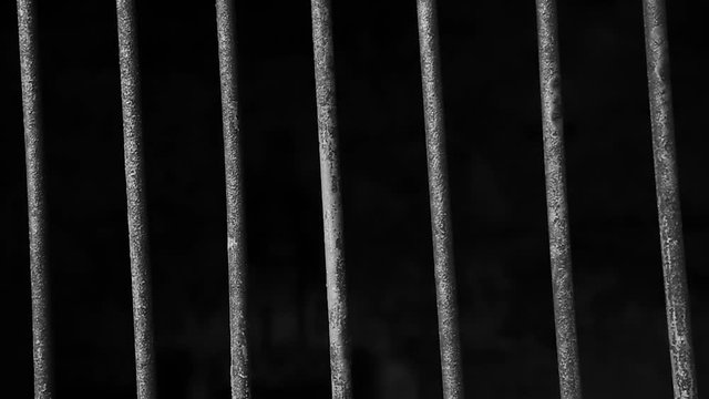 Jail or prison cell. Obsolete gray grunge concrete room. Iron baluster or steel Cage. Old prison bars cell lock background dark black and light