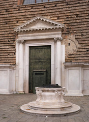 Entrance to the church of San Marcuola. Venice. Italy. In the foreground is a medieval well. In the square in front of the church there is a ferry dock.