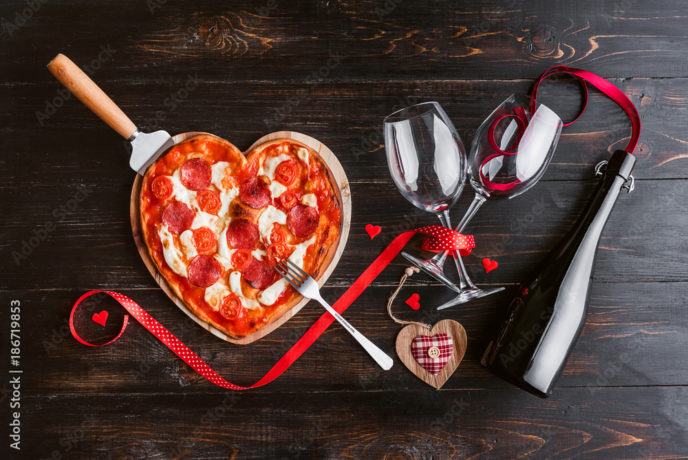 Wall mural a festive dinner of pizza in the shape of a heart and a bottle of wine.