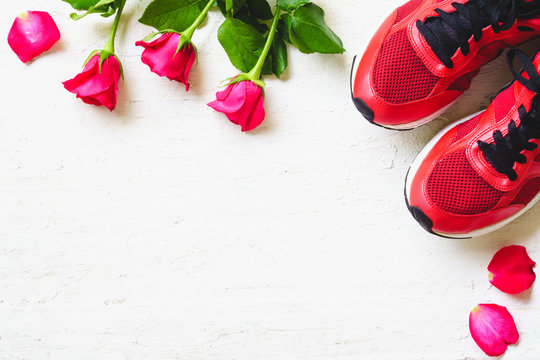 Red sport shoes  and red roses on white wooden background, Valentines sports background and greeting card for any anniversary holiday background concept top view with copy space.