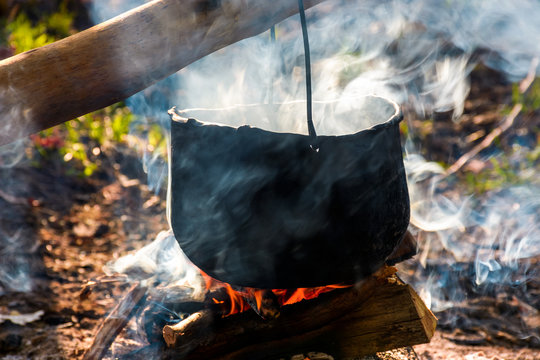 cauldron in steam and smoke on open fire. outdoor cooking concept. old fashioned way to make food