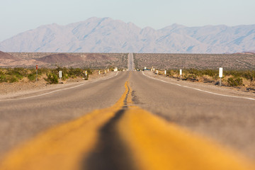 Classic horizontal panorama view of an endless straight road running through the barren scenery of...