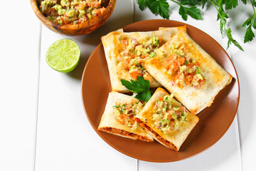 Traditional Mexican dish - chimichanga. Corn cake with minced meat, pepper, onion, garlic, oregano, zira and guacomole sauce from avocado.