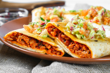 Traditional Mexican dish - chimichanga. Corn cake with minced meat, pepper, onion, garlic, oregano, zira and guacomole sauce from avocado.