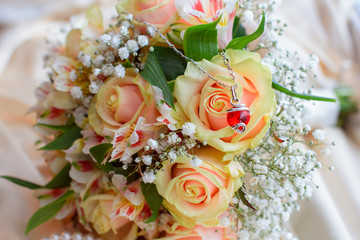 Delicate women's jewelry and accessories on a silk background, next to a bouquet of roses. Beauty and refinement for women 