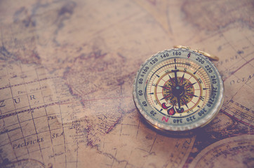 Antique brass compass over map paper background (vintage)