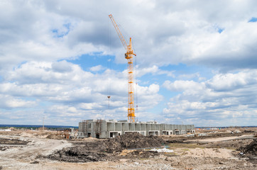 yellow construction crane operating in blue sky and white clouds