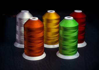 The Spools of colorful silk thread on a black background