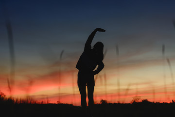 silhouette of woman warm up for exercise in prairie on sunset.