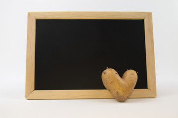 Heart shaped potato in front of a small blackboard
