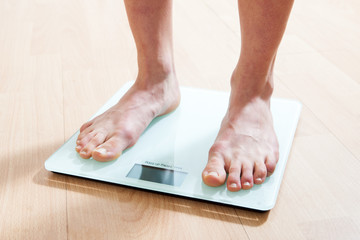 Healthy diet, fitness and weight loss concept. The legs of a young woman on the scales. Checking the weight.
