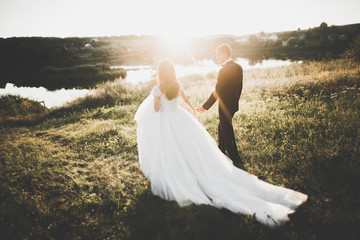 Wedding couple posing on sunset at wedding day. Bride and groom in love