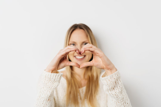 Happy young woman making a heart gesture