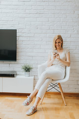 Young woman sitting in the room and using phone