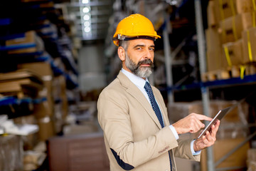 Middle-aged businessman with digital tablet in factory