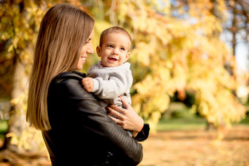 Young mother and baby boy in autumn park