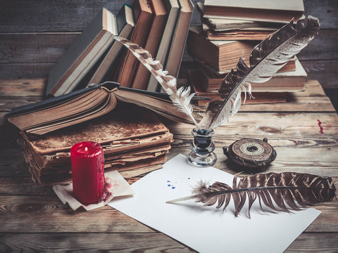Vintage still life. Old books, ink, feathers on a wooden background. Close up. Selective focus. Retro toning.