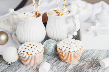 Cups with cacao and marshmallow, cupcakes and different Christmas decorations, wooden background