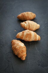 four croissants with a fruit filling, sprinkled with powdered sugar on a dark gray background