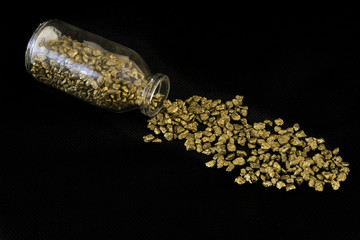 Piedras de oro.
Oro en bruto vertido de una botella de cristal.
