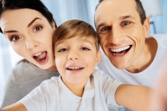 Perfect mood. The close up of a happy young family taking a selfie together, smiling at the camera and making funny faces