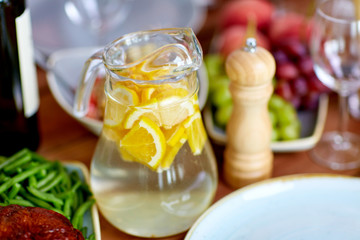 glass jug of lemon water and food on table