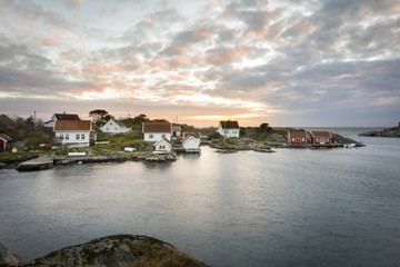 Fototapeta na wymiar Lillesand, Norway - November 7, 2017: Ulvoysund, ocean and old houses on the Ytre Ulvoya in evening light.