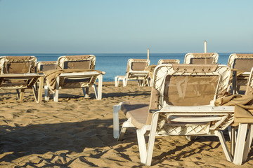 Sun loungers and closed umbrellas at a seaside resort , the calm and relaxed atmosphere of the summer holiday at sunset